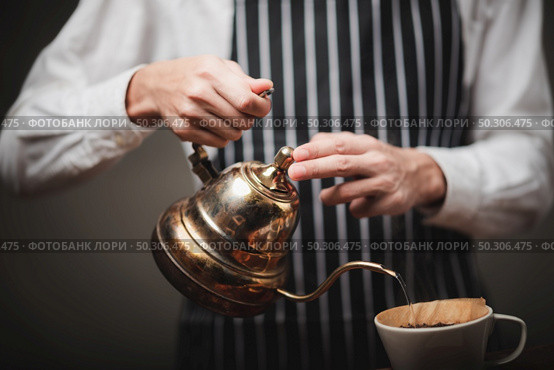 The barista poured hot water from the kettle over the coffee powder to extract the freshly brewed coffee in the coffee shop. Стоковое фото, агентство Ingram Publishing / Фотобанк Лори