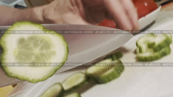 The camera moves with the knife when cutting a fresh green cucumber on a board. Стоковое видео, видеограф Ярославский Максим / Фотобанк Лори