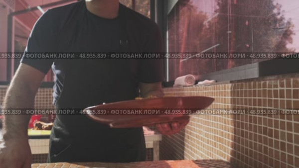 The chef puts carrots with a slotted spoon in a plate with rice from a large cauldron for pilaf. Стоковое видео, видеограф Aleksey Kidisyuk / Фотобанк Лори