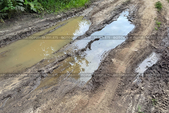 The dirt road is filled with muddy puddles after a rain. Concept of off-road. Стоковое фото, фотограф Ольга Петрова-Апостолова / Фотобанк Лори