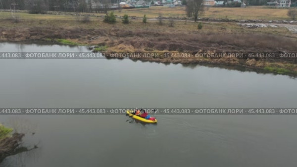 The drone's camera flies over a bright yellow kayak. She is slowly floating along the river with two oarsmen. They row slowly and confidently with oars, guiding the boat along the riverbed. Autumn tourism. Стоковое видео, видеограф Ярославский Максим / Фотобанк Лори