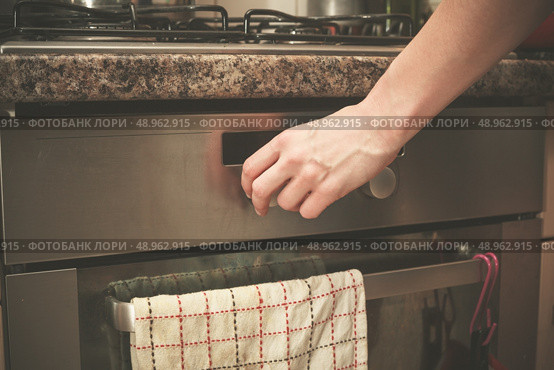 The hand of a young woman is turning the knob on a stove. Стоковое фото, агентство Ingram Publishing / Фотобанк Лори