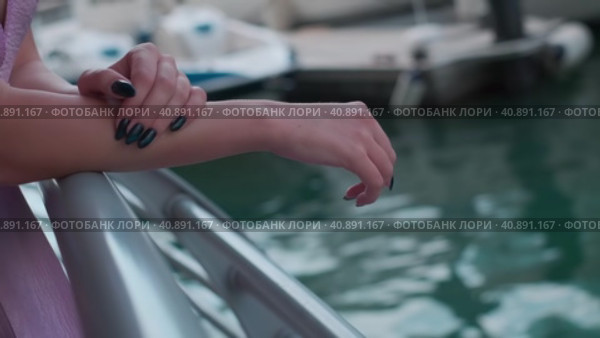 The hands of a young woman in a long purple dress lying on the handrails of a marina in Dubai. Стоковое видео, видеограф Aleksey Kidisyuk / Фотобанк Лори
