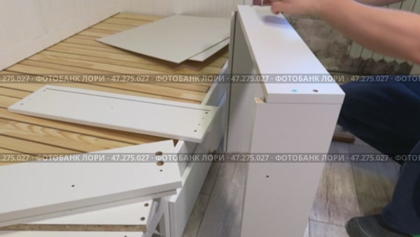 The man is assembling pull-out shelves for the sofa bed from wooden panels. He connects them with furniture hardware. Стоковое видео, видеограф Vadzim Yakubovich / Фотобанк Лори