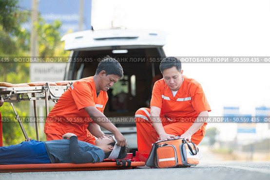 The paramedic  is assisting an injured man in an emergency situation on the road. Стоковое фото, агентство Ingram Publishing / Фотобанк Лори