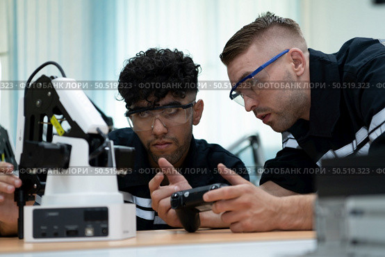 The robotic hand technology teacher is instructing new pupils on how to construct robotic hands for a variety of industrial applications. Стоковое фото, агентство Ingram Publishing / Фотобанк Лори