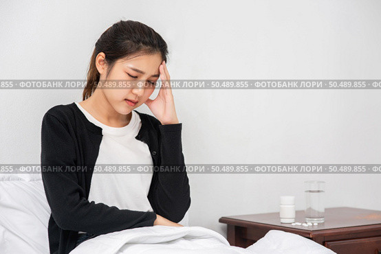 The sick woman had a headache and the hands touched her head on the bed. Стоковое фото, агентство Ingram Publishing / Фотобанк Лори