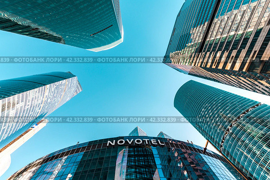 The skyscrapers of Moscow City cover the blue sky and the office of the NOVOTEL company. Russia. Moscow. 03.03.2024. Редакционное фото, фотограф Ярославский Максим / Фотобанк Лори