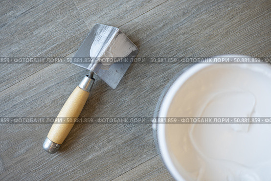 The spatula for the corners and the jar with putty. Laminated grey background. Repair concept, repair goods stores. Top down view. Copy space. Стоковое фото, фотограф Екатерина Топорова / Фотобанк Лори