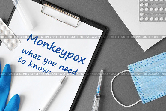 The word Monkeypox what you need to know on Gray modern doctor desk table background. Mask, notepad, syringe and supplies. Monkey pox spreading. Medicine and healthcare, medical education. Top view. Стоковое фото, фотограф Марина Демидюк / Фотобанк Лори