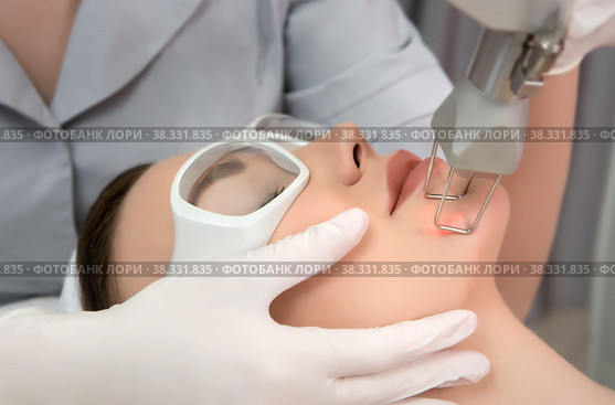 Therapist beautician makes a laser rejuvenation for the model by apparatus in a beauty salon. Стоковое фото, фотограф Юлия Тарасова / Фотобанк Лори