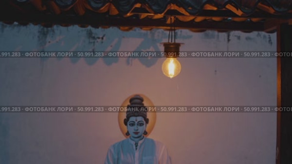 Theyyam artist posing with traditional Theyyam painting on a rooftop at sunset, illuminated by a single light bulb, creating a serene and spiritual atmosphere. Стоковое AI-видео, аниматор Данил Руденко / Фотобанк Лори