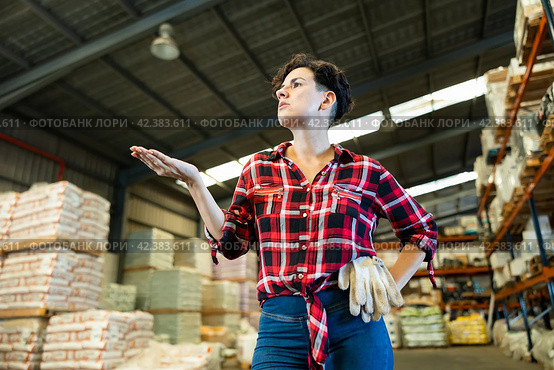 Thoughtful female storekeeper looking for tedious goods in building materials warehouse indoor. Стоковое фото, фотограф Яков Филимонов / Фотобанк Лори