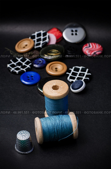 thread and buttons for sewing master on black background.Selective focus. working tool dressmaker. Стоковое фото, агентство Ingram Publishing / Фотобанк Лори