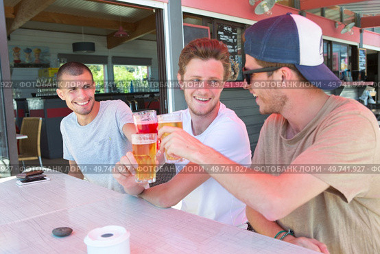 three male friends relax drinking beer out on restaurant terrace. Стоковое фото, агентство Ingram Publishing / Фотобанк Лори