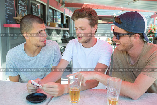 three men drinking beer at terrace bar. Стоковое фото, агентство Ingram Publishing / Фотобанк Лори