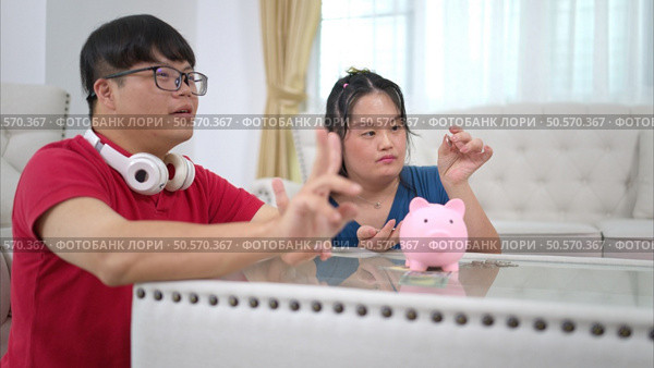 Three siblings save money by putting it in a piggy bank, This is an activity that parents teach their children about saving money. Стоковое фото, агентство Ingram Publishing / Фотобанк Лори