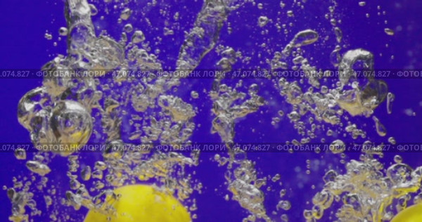 Throwing lemons into water on blue background. Making lemon juice. Стоковое видео, видеограф Владимир Ковальчук / Фотобанк Лори