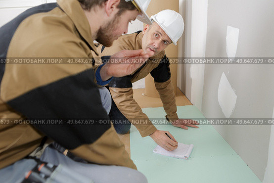 tiler and co-worker at indoor floor tiling renovation. Стоковое фото, агентство Ingram Publishing / Фотобанк Лори