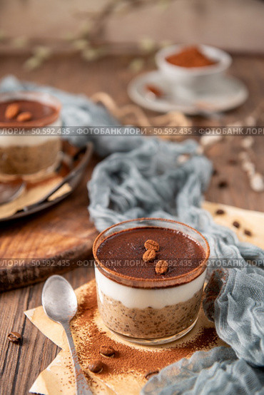 Tiramisu chia pudding in a glass, topped with cocoa powder and coffee beans, styled with a rustic background, soft fabric, and a vintage spoon. Стоковое фото, агентство Ingram Publishing / Фотобанк Лори