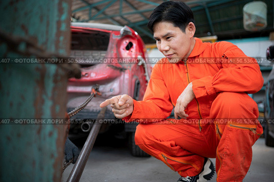 To return the automobile body to its former shape, an auto repair mechanic uses a machine to pull the car body caused by a heavy collision until it is deformed. Стоковое фото, агентство Ingram Publishing / Фотобанк Лори