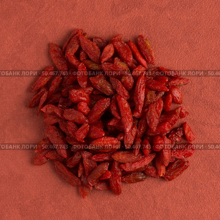 Top view of circle of dry red goji berries against red vinyl background. Стоковое фото, агентство Ingram Publishing / Фотобанк Лори