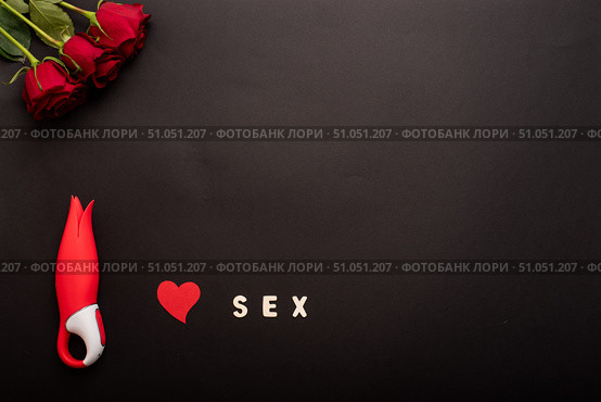 Top view of roses, clitoral vibrator in the form of a red tulip, heart and the inscription clitoris on a black background. Flat lay. Copy space. Стоковое фото, фотограф Михаил Решетников / Фотобанк Лори