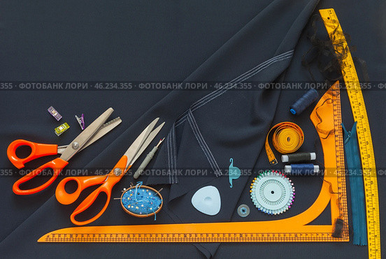 Top view of sewing accessories and materials for sew and cutting on blue silk fabric - threads, needles, scissors, pattern, pincushion. Sewing as a hobby. Flat lay, closeup, copy space. Стоковое фото, фотограф Виктория Катьянова / Фотобанк Лори