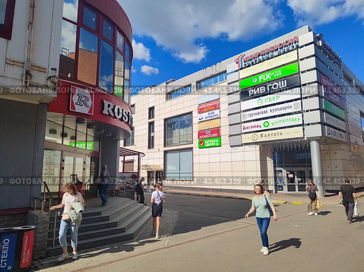 Торговый центр с рекламными вывесками и парковка, Москва, прохожие летом (2024 год). Редакционное фото, фотограф Ирина Терентьева / Фотобанк Лори