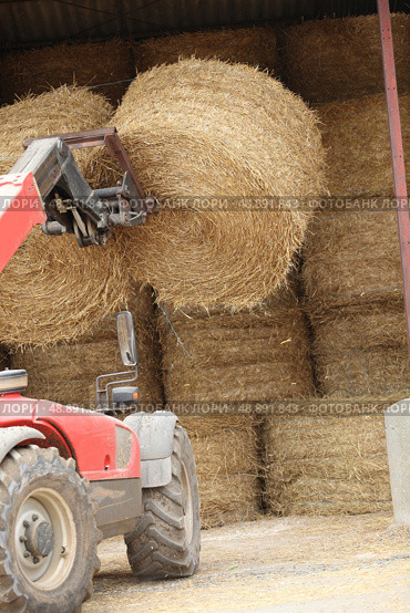 Tractor lifting bail of hay. Стоковое фото, агентство Ingram Publishing / Фотобанк Лори
