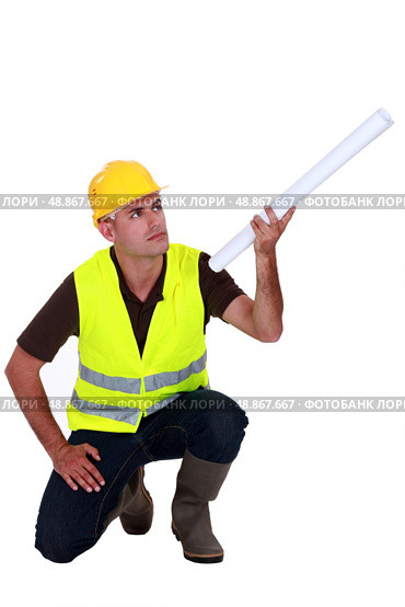 Tradesman holding up a rolled-up blueprint. Стоковое фото, агентство Ingram Publishing / Фотобанк Лори
