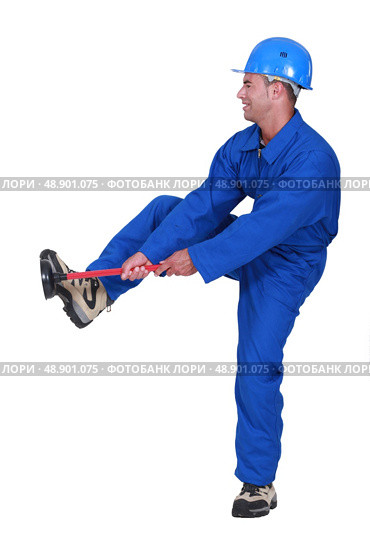 Tradesman unblocking a stoppage using a plunger. Стоковое фото, агентство Ingram Publishing / Фотобанк Лори