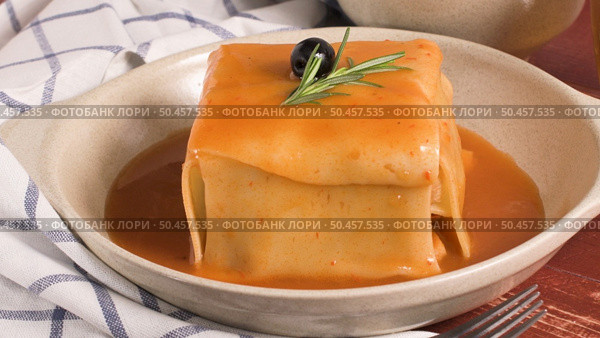 Traditional Portuguese snack food. Francesinha sandwich of bread, cheese, pork, ham, sausages, with tomato beer sauce and French fries. With beer and potatoes. On table. Стоковое фото, агентство Ingram Publishing / Фотобанк Лори