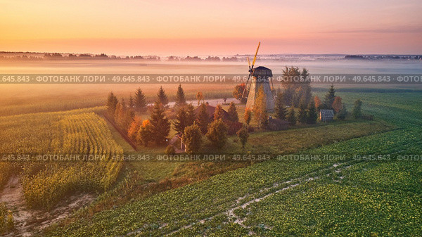 Traditional Wooden Windmill Morning Landscape. Rural colorful Sunrise, Foggy green fields. Dudutki village, Minsk Region, Belarus. Стоковое фото, агентство Ingram Publishing / Фотобанк Лори