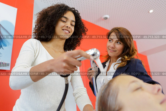 trainee hairdresser washing female clients hair. Стоковое фото, агентство Ingram Publishing / Фотобанк Лори
