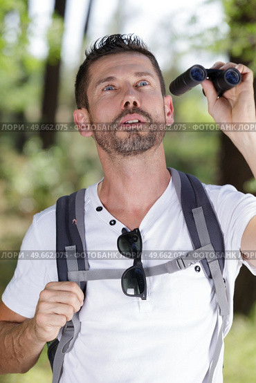 traveler man looks through a binoculars. Стоковое фото, агентство Ingram Publishing / Фотобанк Лори
