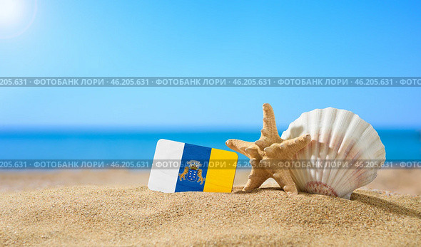 Tropical beach with seashells and Canaries flag. The concept of a paradise vacation on the beaches of Canaries. Стоковое фото, фотограф Никита Бурденков / Фотобанк Лори