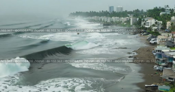 tsunami storm waves crash onto the shore of a residential area filled with apartment buildings, causing destruction, aerial view. Стоковое AI-видео, аниматор Александр Довянский / Фотобанк Лори