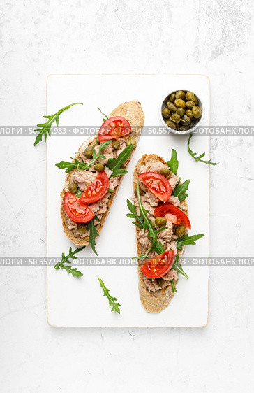 Tuna caper toasts with arugula, tomatoes and whole rye bread, top view. Стоковое фото, агентство Ingram Publishing / Фотобанк Лори