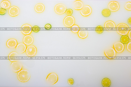 Turbid soapy water in the bath with slices of lemon and lime top view in full frame. Citrus. Spa with milk in the bath for rejuvenation. Стоковое фото, фотограф Михаил Решетников / Фотобанк Лори