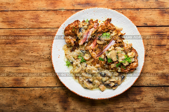 Turkey meat in cheese breading with mushroom sauce.Turkey schnitzel on rustic wooden table. Turkey steak with fried mushrooms. Стоковое фото, агентство Ingram Publishing / Фотобанк Лори