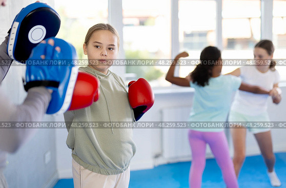 Tween girl in boxing gloves practicing punches on focus mitts with instructor. Стоковое фото, фотограф Яков Филимонов / Фотобанк Лори