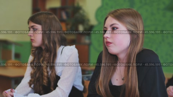 Two attentive high school girls actively engaged in a classroom lesson, absorbing the teacher's instruction during the school day. Стоковое видео, видеограф Mikhail Davidovich / Фотобанк Лори