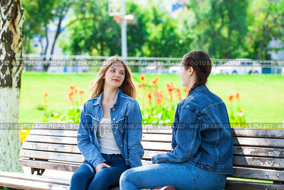 Two beautiful girlfriends are talking in a park sitting on a bench. Стоковое фото, фотограф Андрей Аркуша / Фотобанк Лори