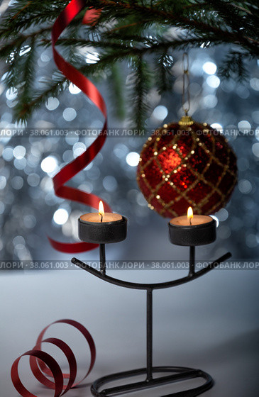 Two burning candles in a candlestick, a red ball and streamer ribbon on the Christmas tree. Стоковое фото, фотограф Юлия Бабкина / Фотобанк Лори
