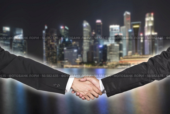 Two businessman shaking hands over blur night cityscape. Стоковое фото, агентство Ingram Publishing / Фотобанк Лори