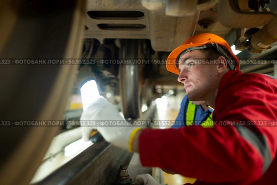 Two engineers for electric trains After detecting difficulties with the electric train’s machinery use searchlights to locate and check damaged sections. In the electric train repair shop. Стоковое фото, агентство Ingram Publishing / Фотобанк Лори