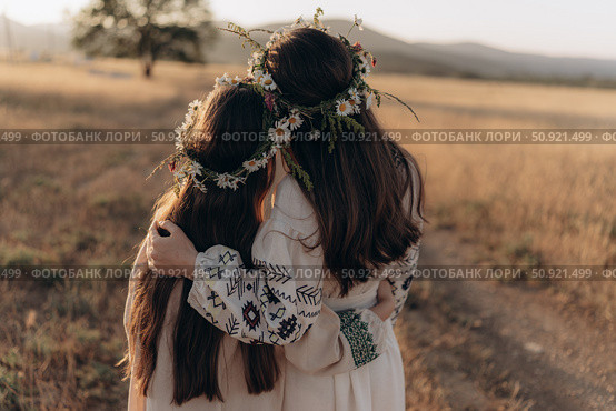 Two girls in folk dresses and flower wreaths in a field. Стоковое фото, фотограф София Тюленева / Фотобанк Лори