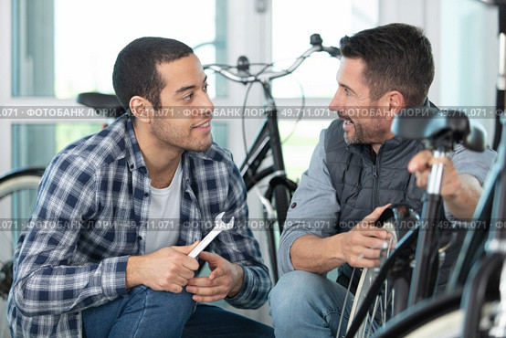 two happy mechanics with tools in a bike repair station. Стоковое фото, агентство Ingram Publishing / Фотобанк Лори
