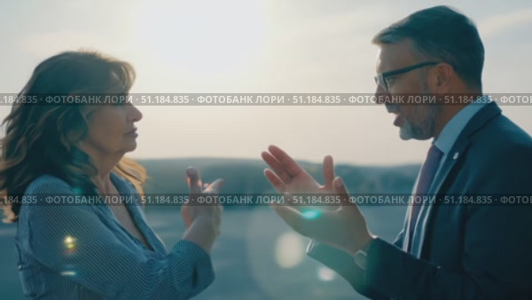 Two professionals enjoy an animated discussion outdoors, illuminated by warm afternoon sunlight, surrounded by nature's beauty. Стоковое AI-видео, аниматор Данила Большаков / Фотобанк Лори